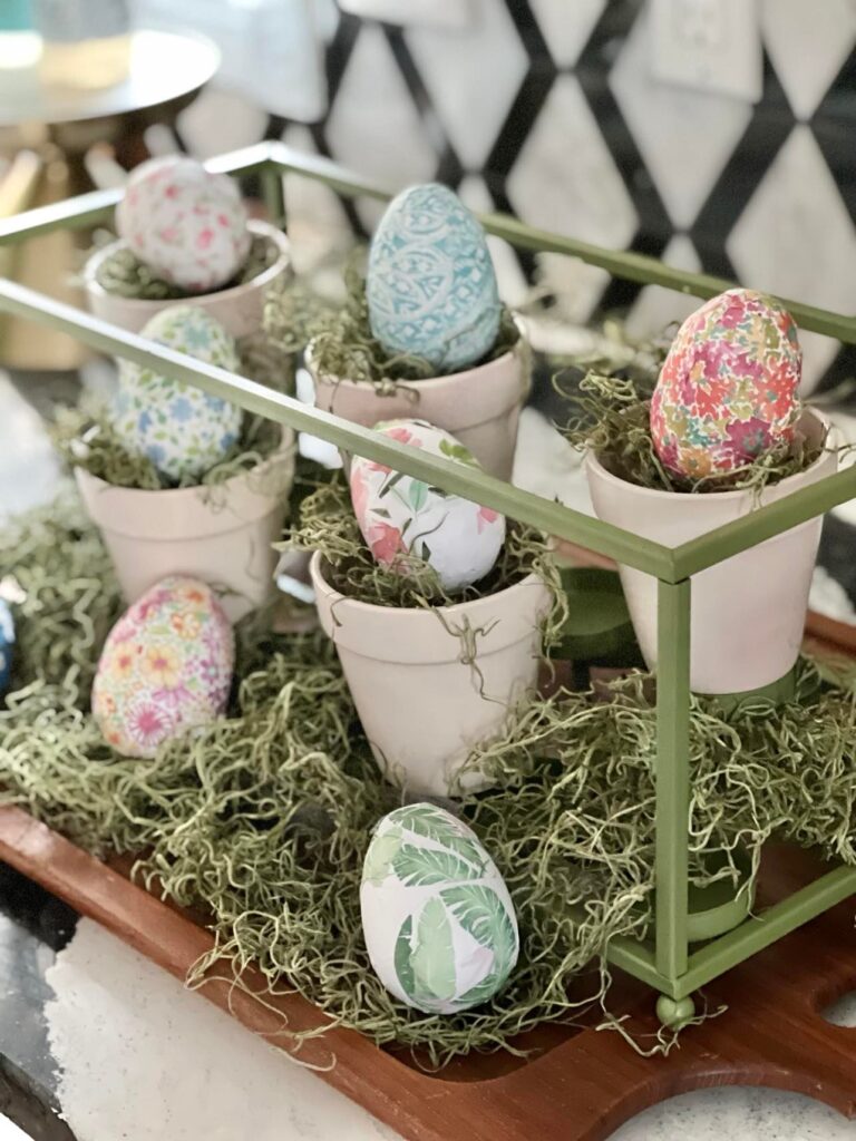 A centerpiece with a green frame and pink pots.