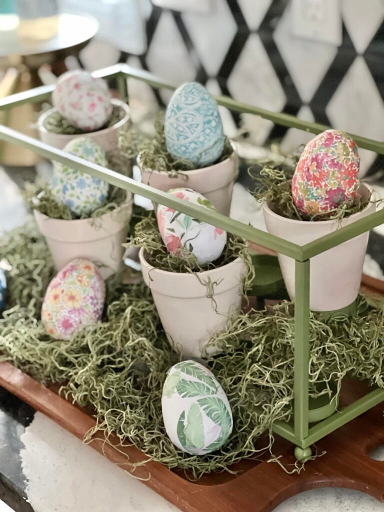 Paper covered Easter eggs sitting in terra cotta pots inside the Easter table centerpiece.