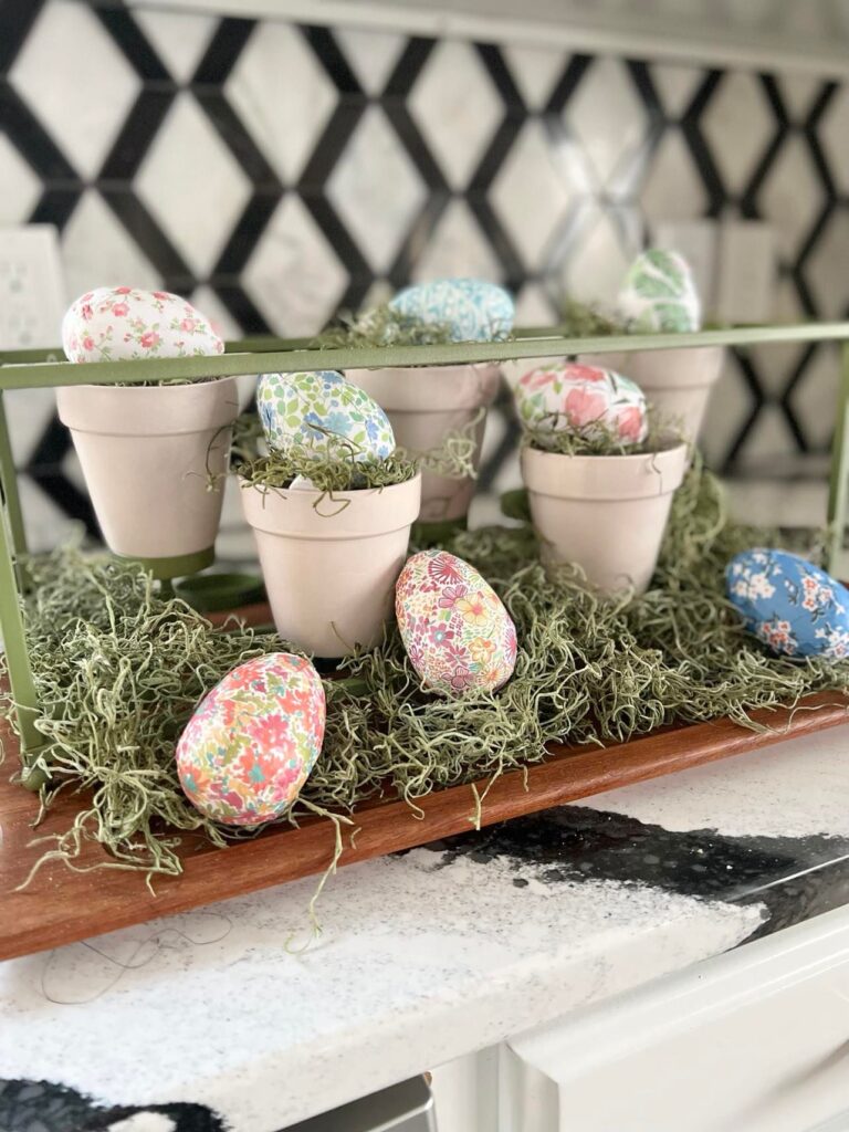 Paper covered Easter eggs sitting in the middle of the Easter table centerpiece.