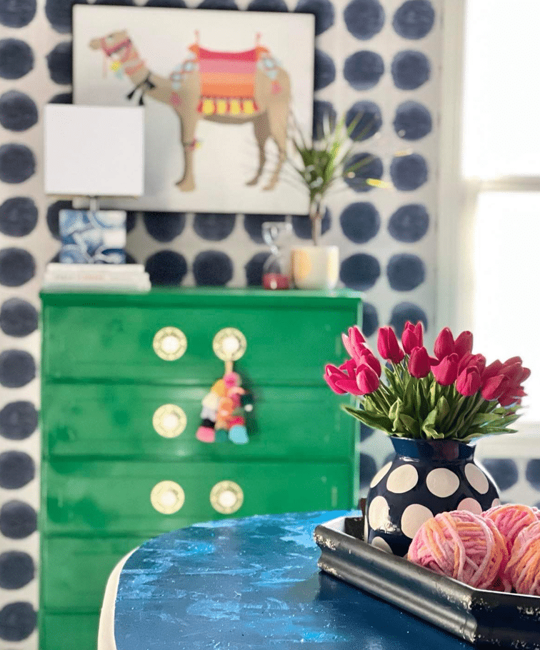 An emerald green dresser sitting in front of a blue table.