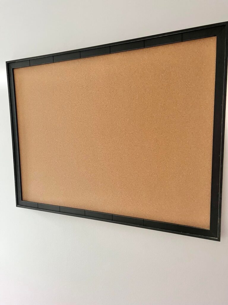 A cork bulletin board with a black frame