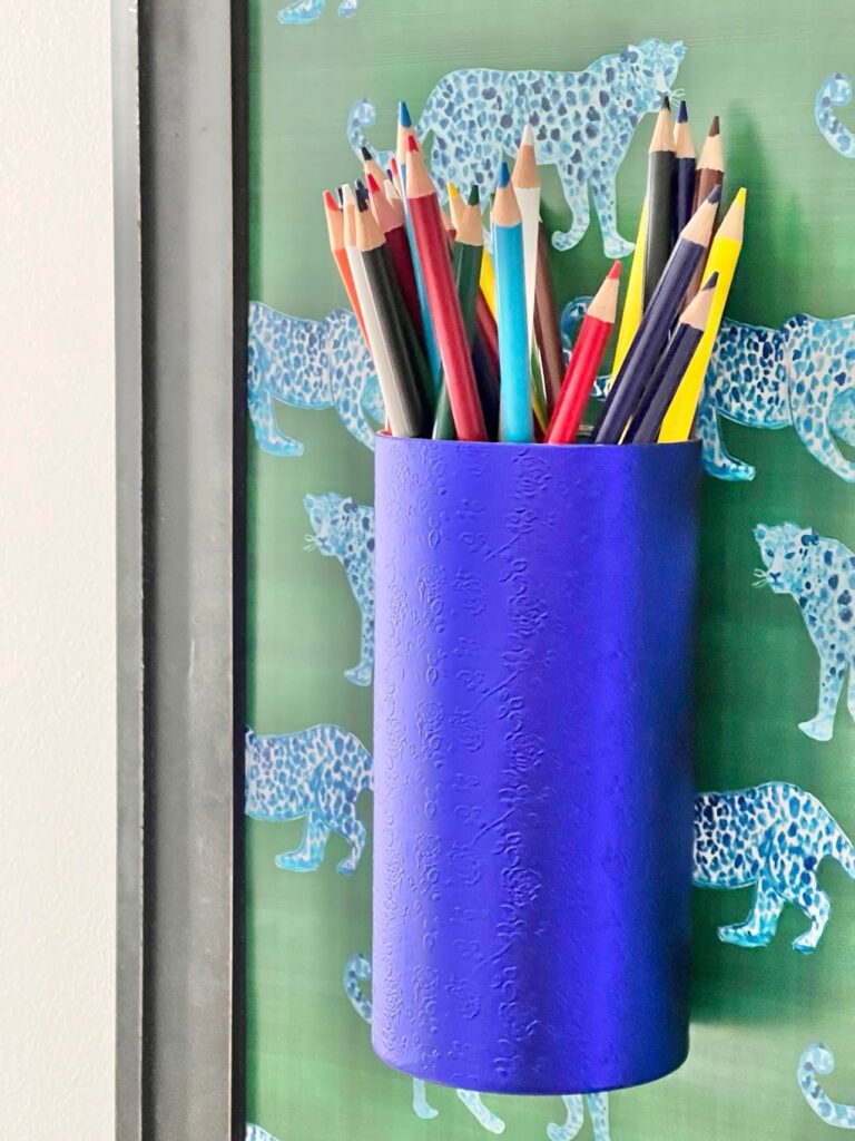 A blue cardboard cylinder holding colored pencils.