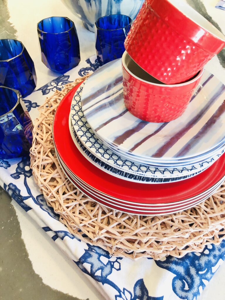 Blue melamine glasses, blush pink placemats, blue and white abstract plates, and bright red ramekins make up the dinnerware for the Memorial Day Table.