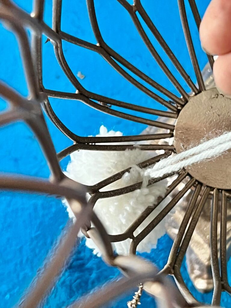 Tying a white pom-pom onto the vase .