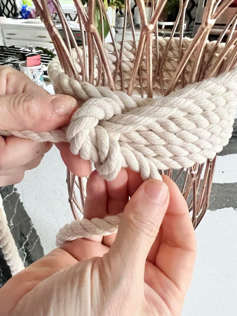 Tying a knot with the cotton rope on the trash to treasure vase.