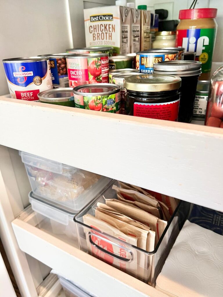 Cans and bottles of food sitting in a roll out pantry drawer.