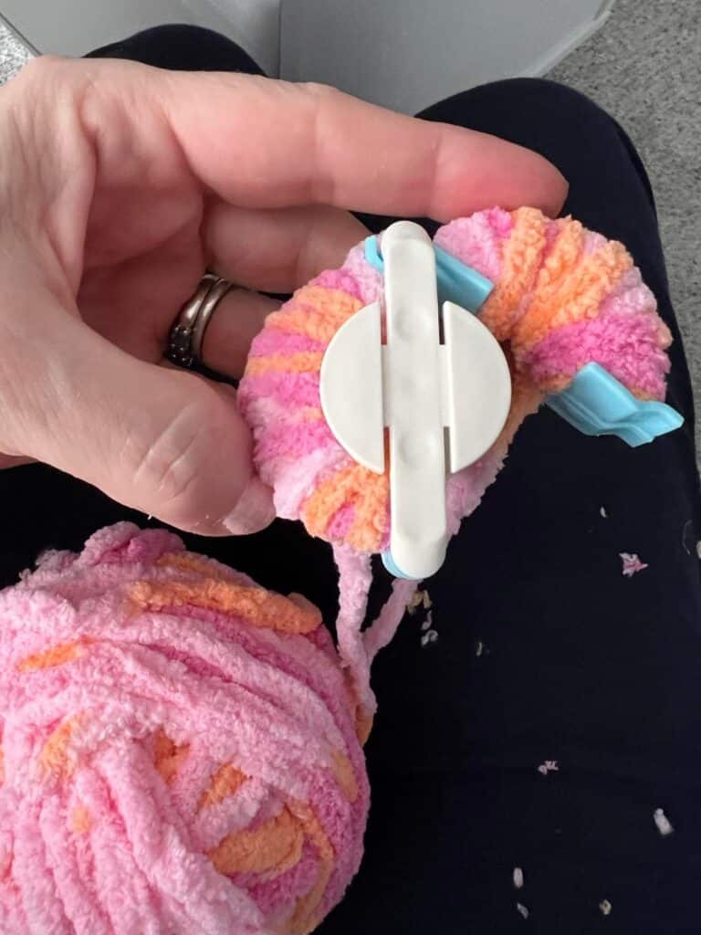 Multi-colored chenille yarn on a pom-pom maker.