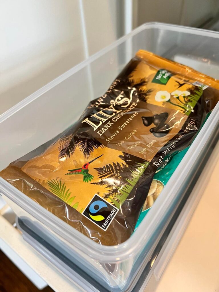 A bag of chocolate chips stored in a sealed clear container. This is a great tip when you organize a pantry with pull-out drawers.