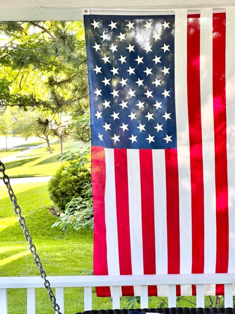 The American flag hanging on the side of the front porch.