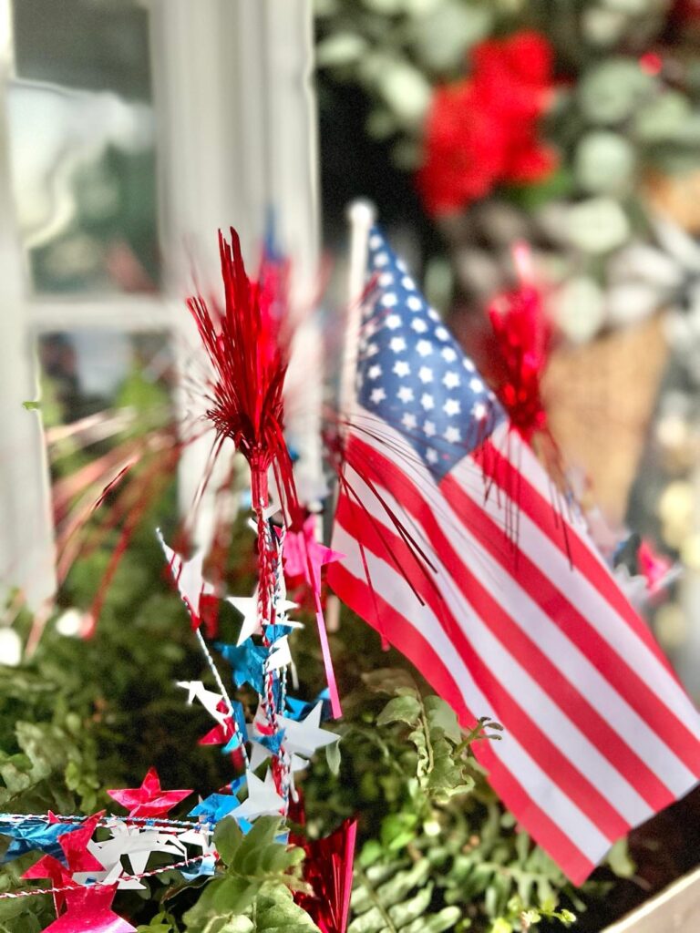 A small American flag sticking out of a copper planter used to decorate the front porch for July 4th.