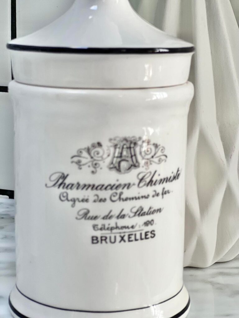 A white apothecary jar with French script on the front.
