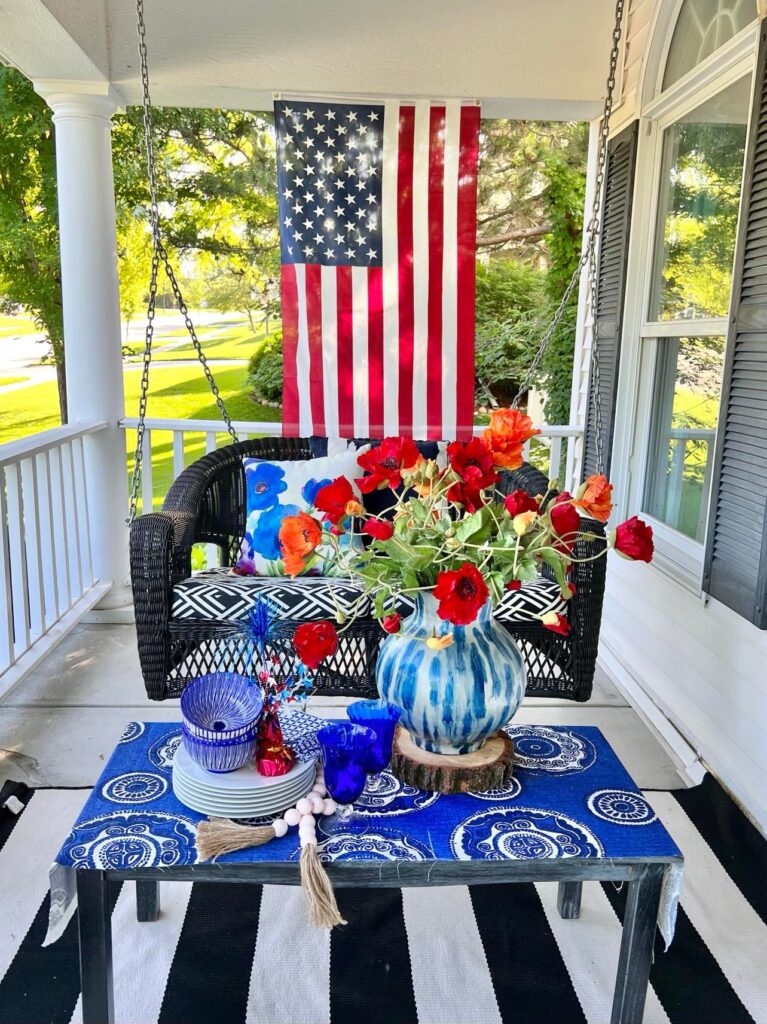 A front shot of the black porch swing with the American flag hanging behind it.