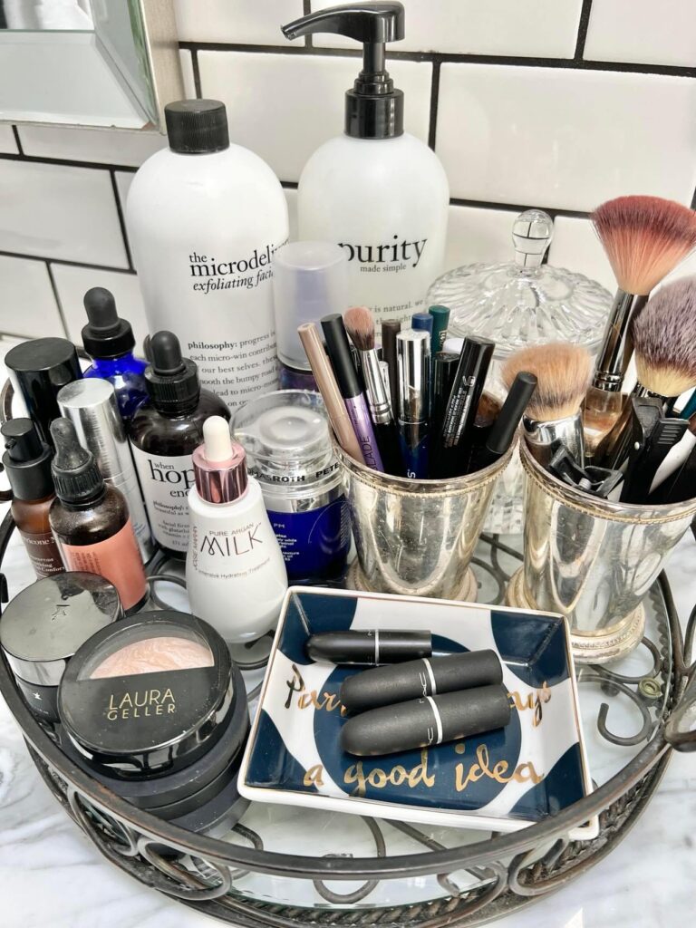 Face wash, lotions, serums, make-up brushes, and make-up gathered onto a tray for a budget-friendly bathroom spa experience.