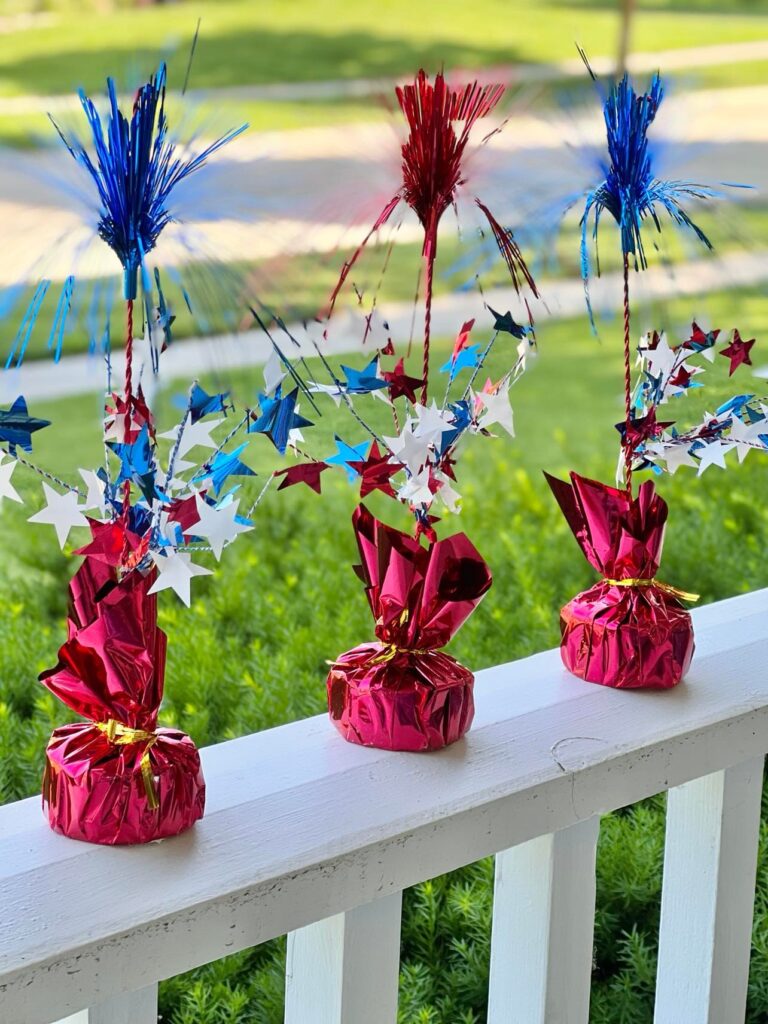 Decorative red, white, and blue stars sitting on a white porch railing.