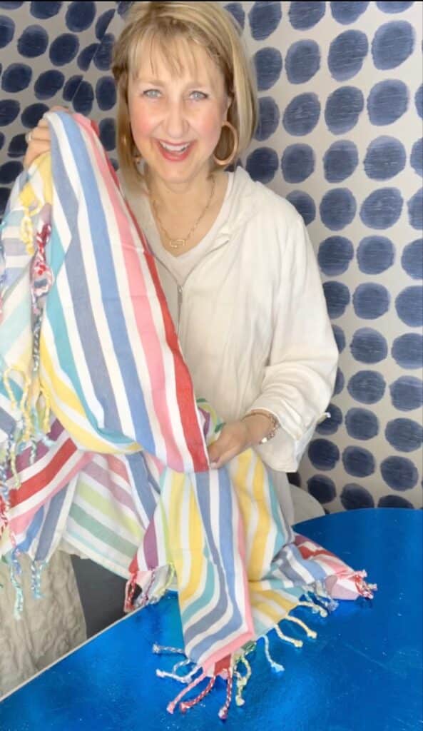 Missy holding a multi-colored striped beach towel.