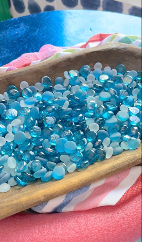 Shades of blue glass pebbles sitting inside the dough bowl for the summertime dough bowl idea.