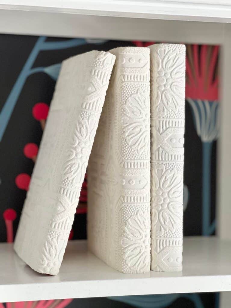 Three white books sitting vertically are a great step in styling bookshelves for summer.