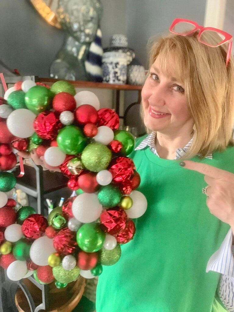 Missy pointing toward a wreath made up of red, green, and white ornament balls.