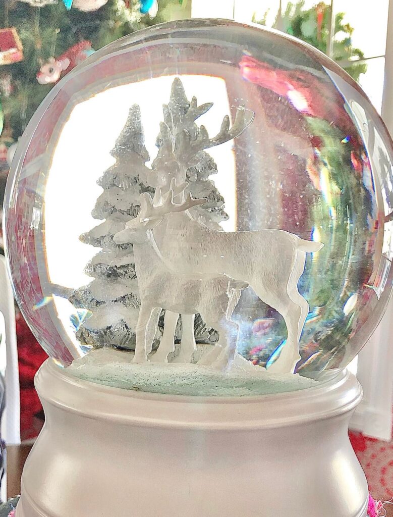 A white snow globe with reindeer inside.