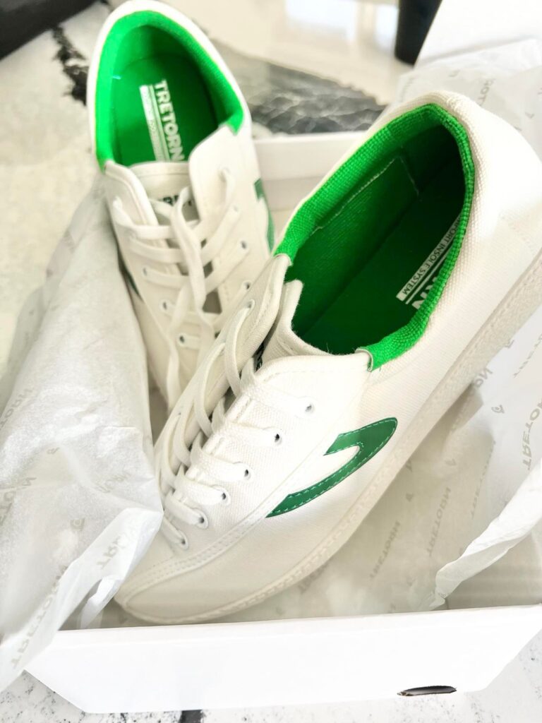 New White and Green Sneakers sitting in their box.