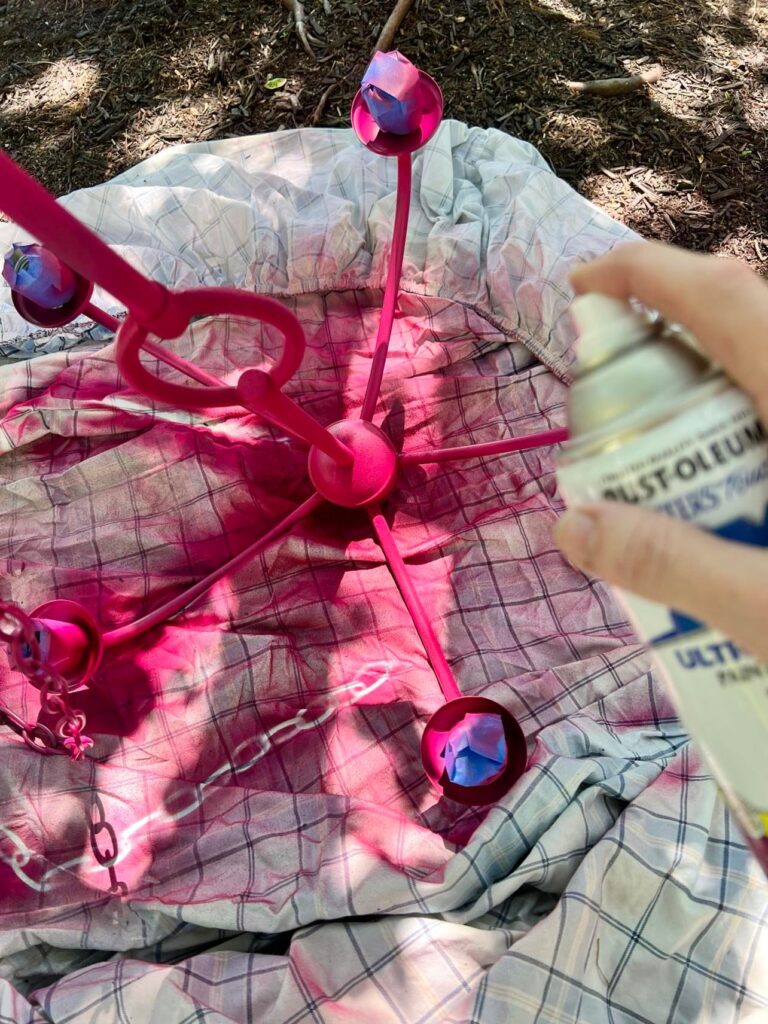 Spray painting the light fixture with the magenta spray paint.