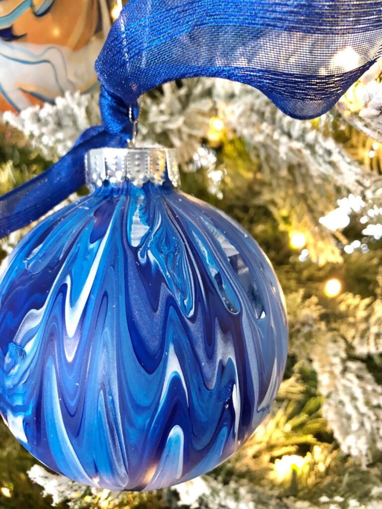 A blue and white ornament hanging on a tree.