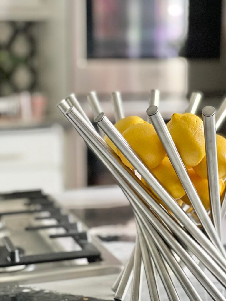 Modern stainless steel fruit bowl sitting on a kitchen island countertop and holding several yellow lemons is a fresh take on kitchen island decor.