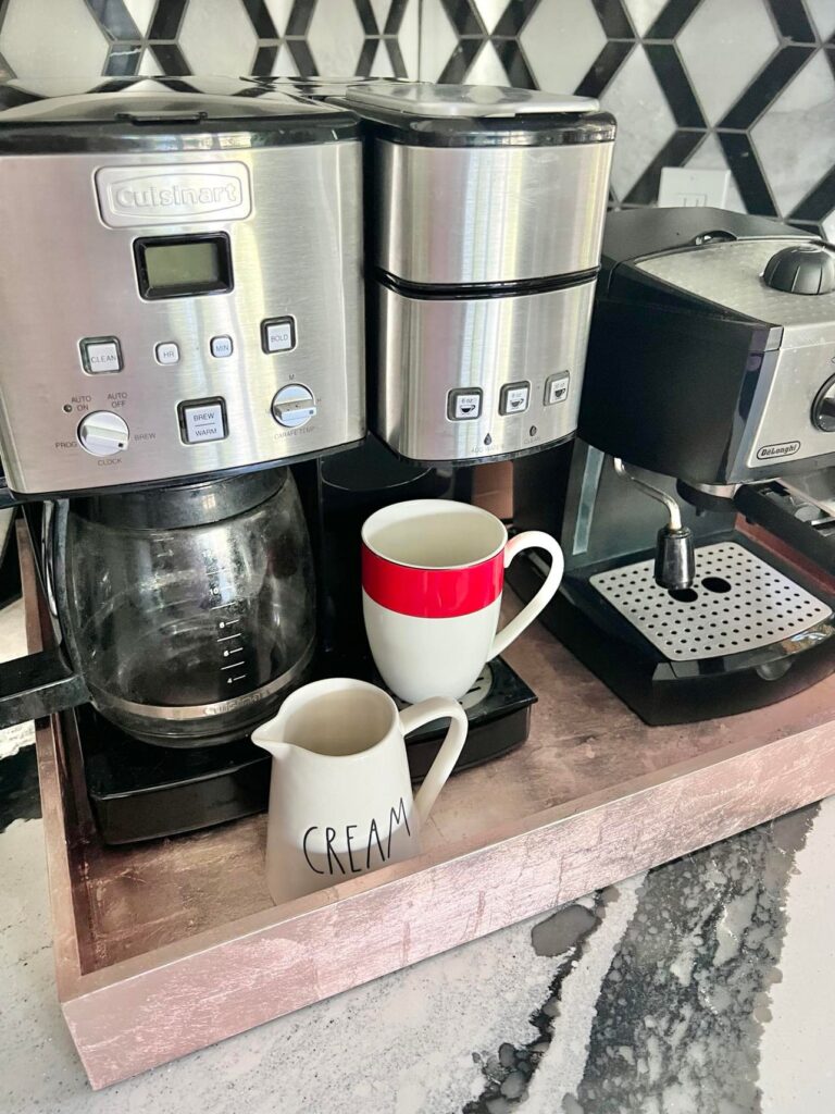 A rose gold decorative tray holding a coffee maker and cappuccino maker.