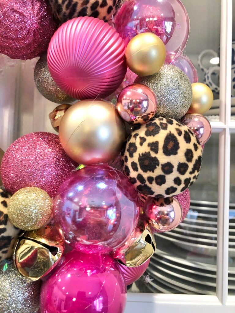 A wreath made of pink, gold, and animal print ornament balls.