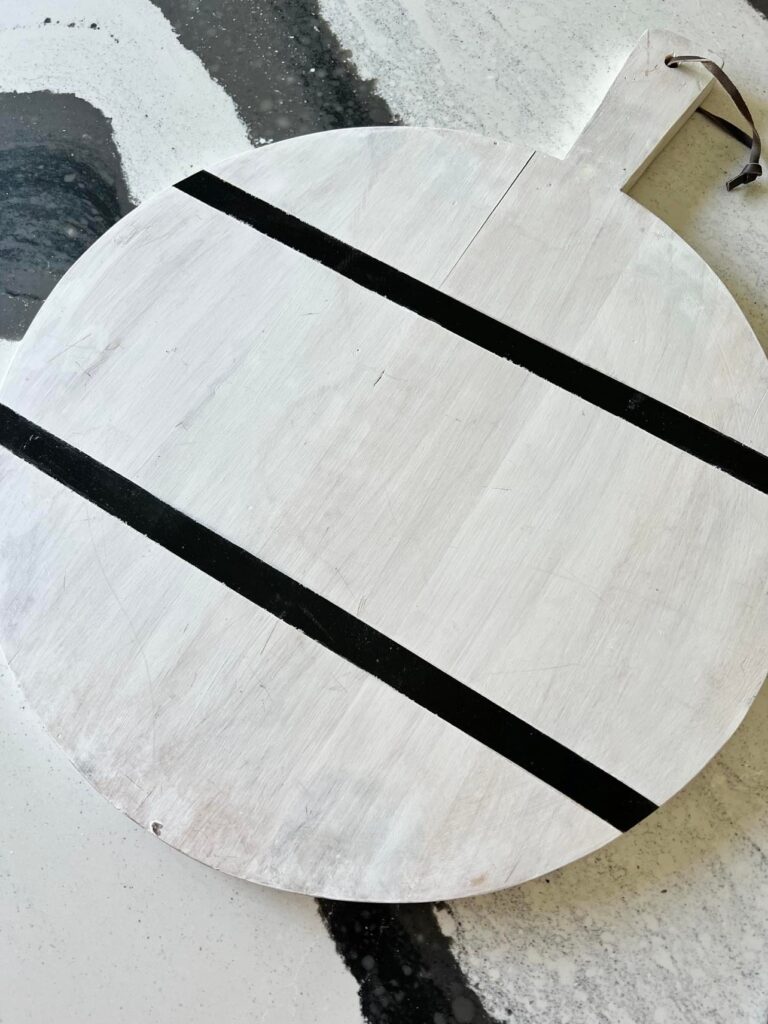 A white wooden pizza peel serving as a decorative tray in the kitchen.