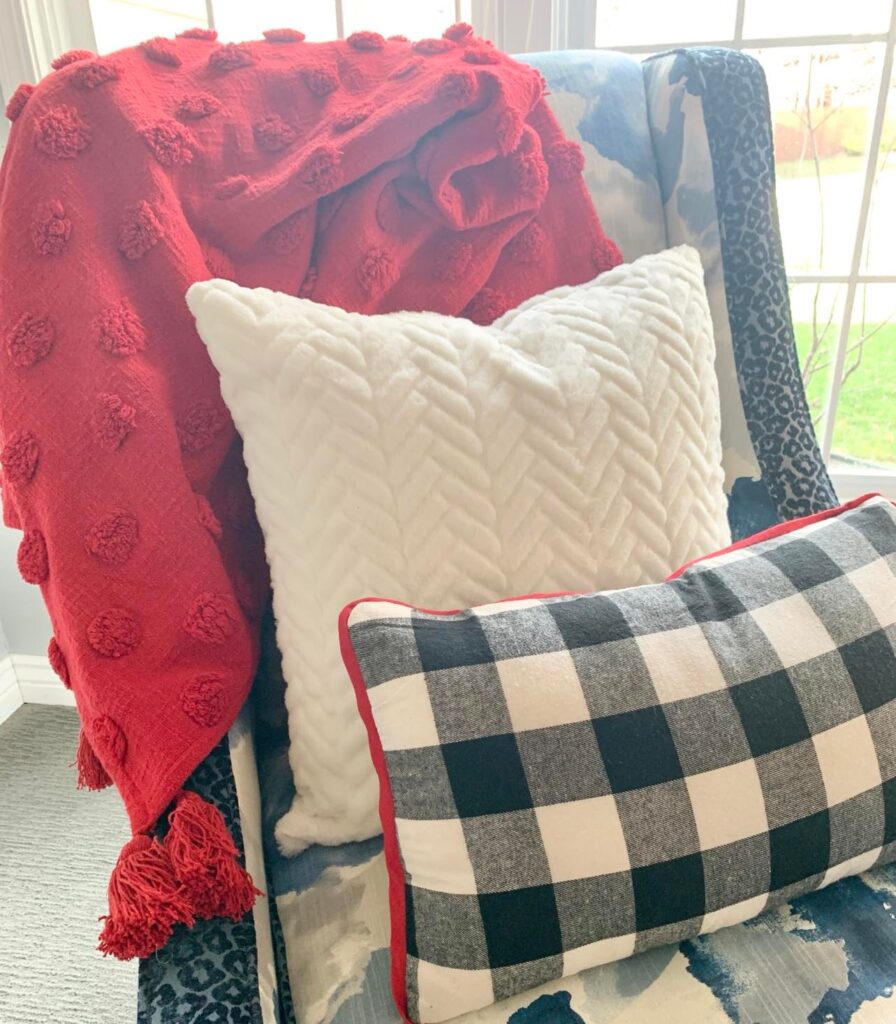 A red throw blanket, white pillow, and black and white plaid pillow.