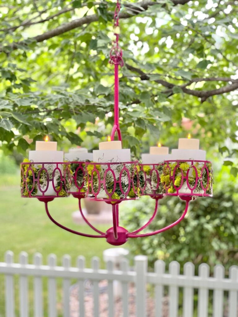 The completed light fixture makeover hanging from a tree branch outdoors.