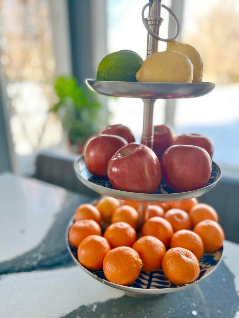 Red apples, oranges, and lemons displayed as colorful accents on a three tiered tray in the kitchen.