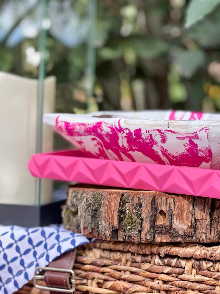 Side view of white painted dough bowl with pink wallpaper cut-outs glued on.