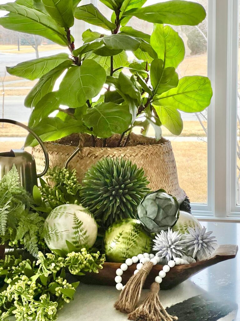 Faux greenery, wood bead garland, and decorative orbs fill a dough bowl to overflowing.