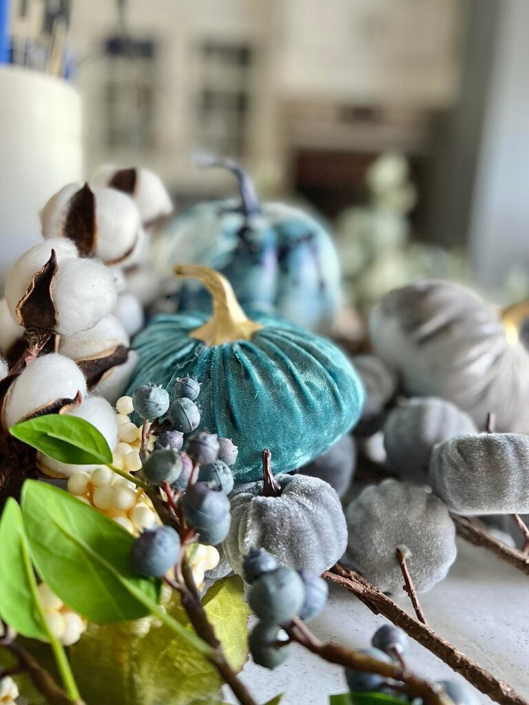 Fall velvet pumpkins displayed on. a decorated bookshelf.