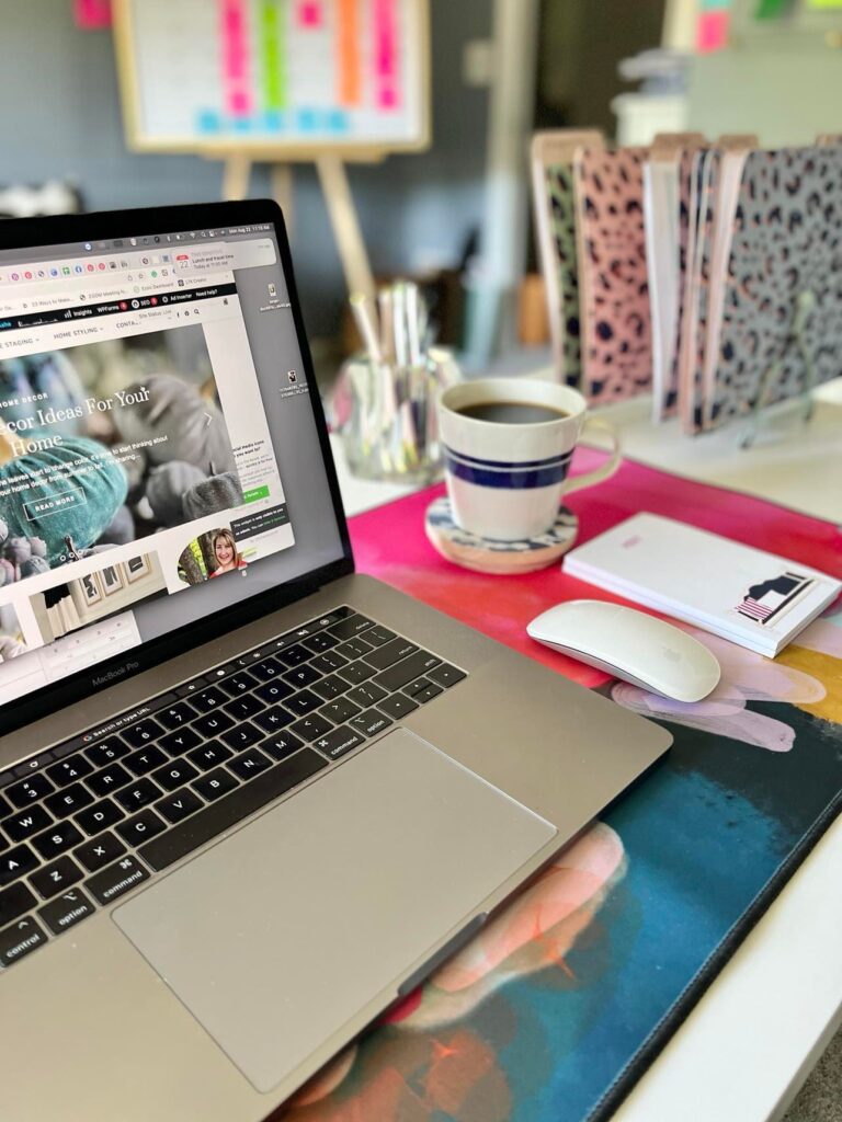 The top of a bedroom desk with laptop, file folders, notepad, and a cup of coffee.