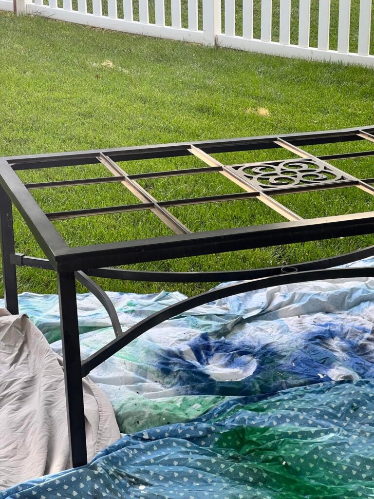 The patio table frame getting a coat of black spray paint.