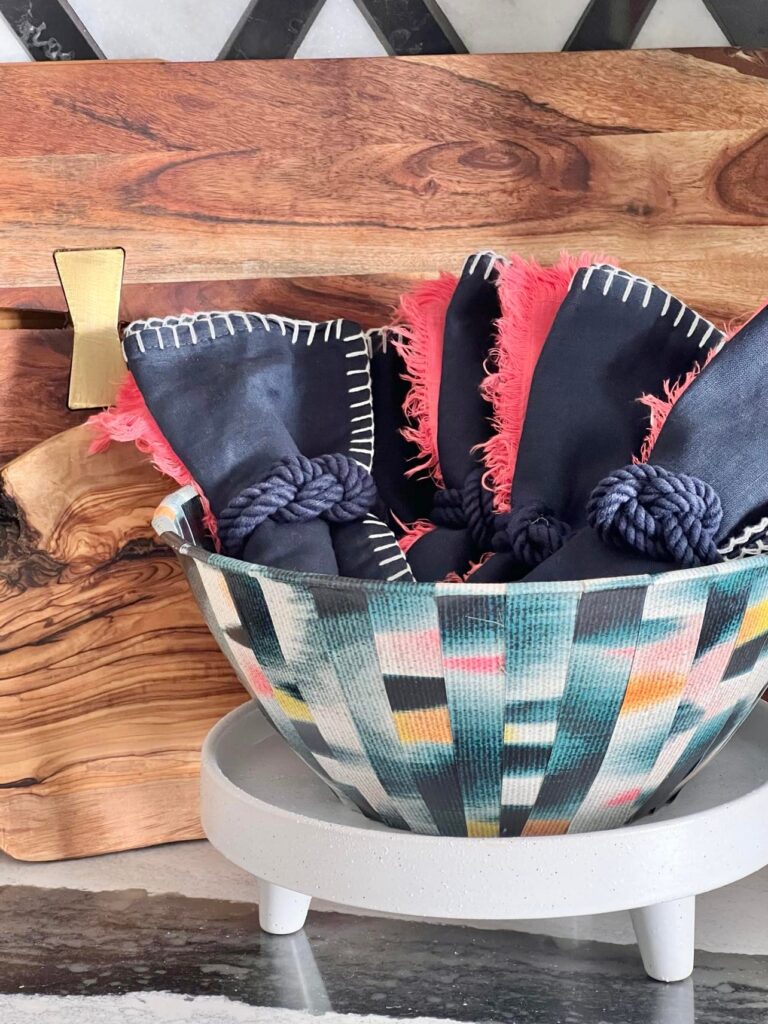 A bowl decorated with wallpaper strips and holding cloth napkins.