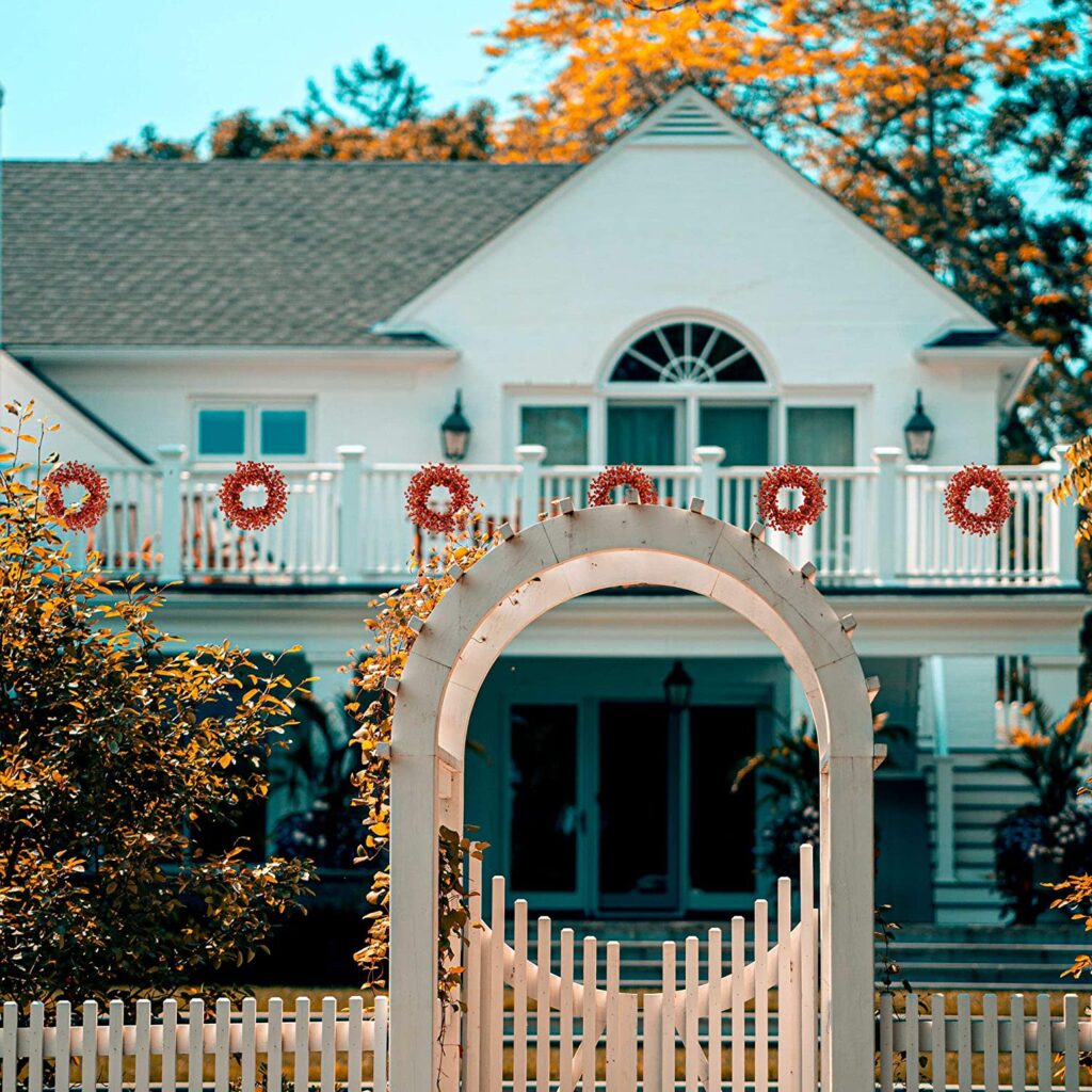 Mixed berry wreaths from Amazon hanging from a white balcony.