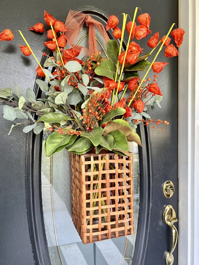 Florals displayed in a wooden lantern and hanging on the glass insert as DIY door decor.