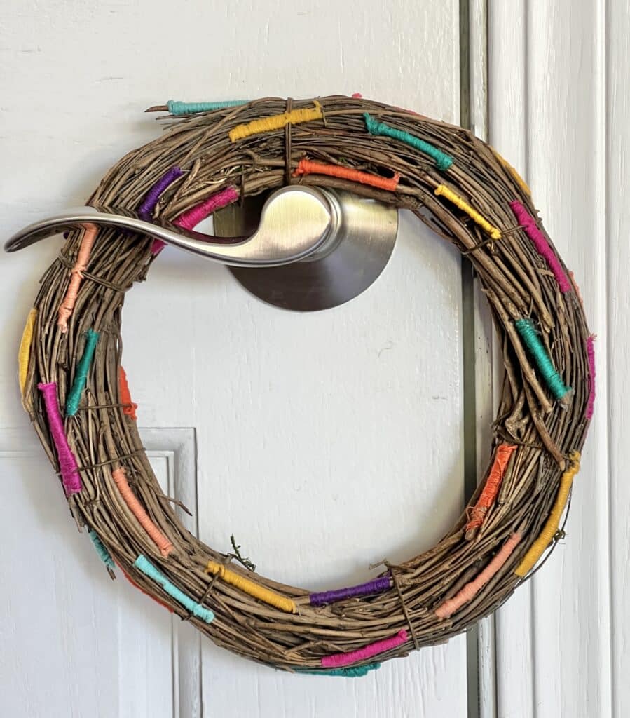 The threaded grapevine wreath hanging on a door handle.