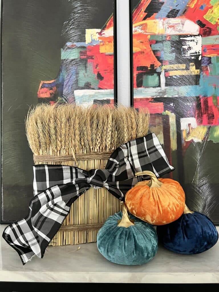 A close up of a large wheat bundles surrounded by colorful velvet pumpkins.