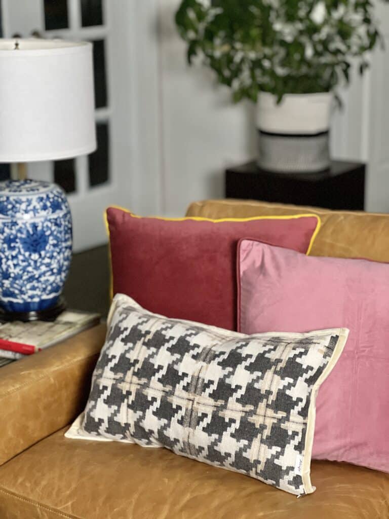 Two pink velvet pillows and one houndstooth pillow nestled into one end of the sofa.