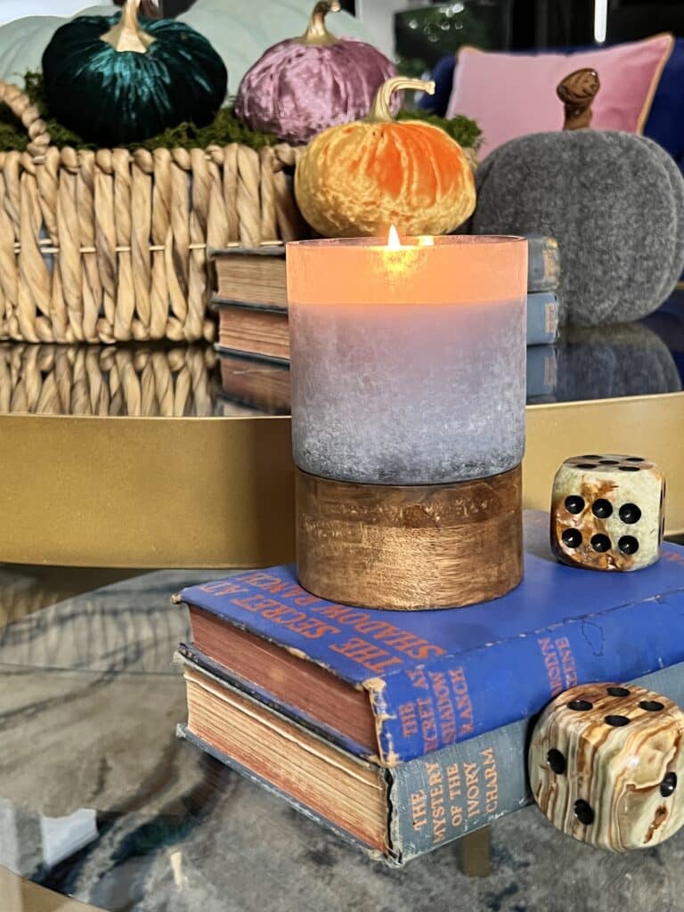 A pumpkin spice candle sits on a stack of vintage Nancy Drew books.