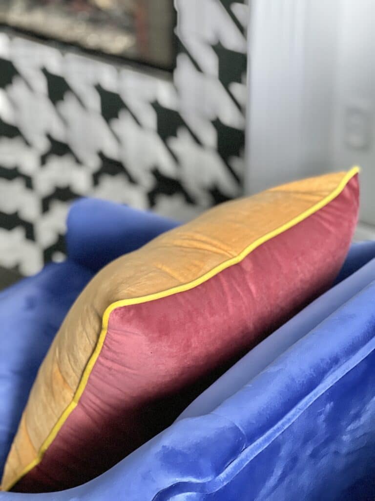 A reversible pillow on a blue chair in the living room.