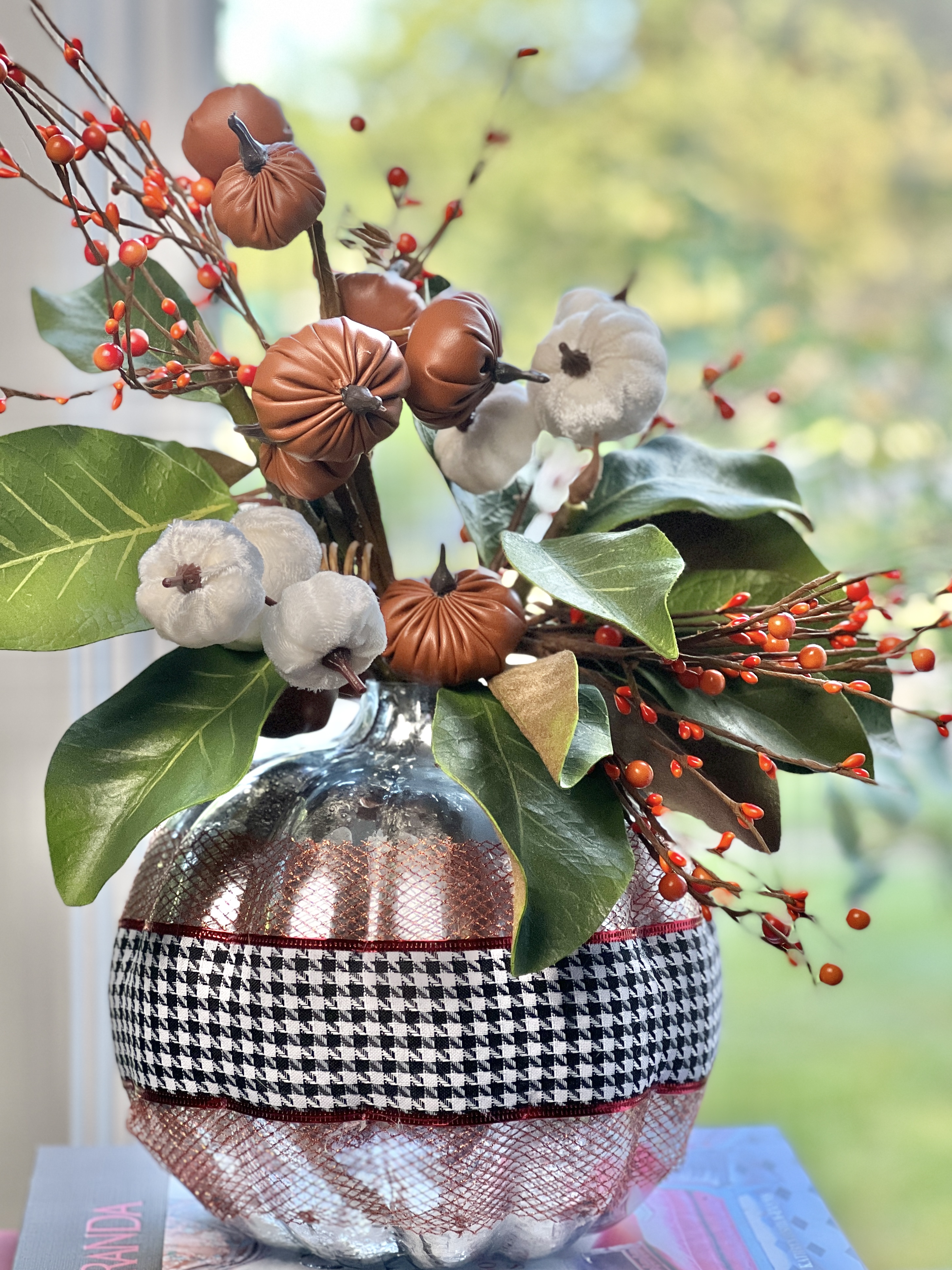 The completed DIY Pumpkin vase with ribbon, velvet and leather pumpkins, and magnolia leaves.