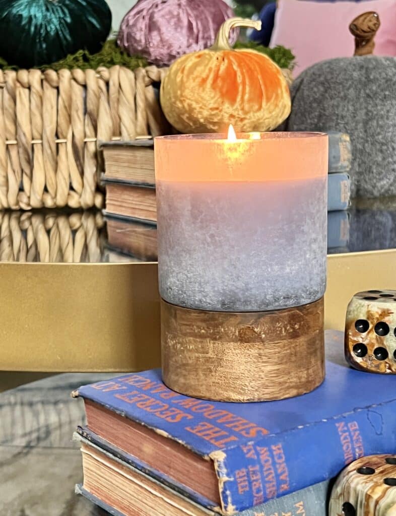 A jar candle sitting on top of some blue vintage books.