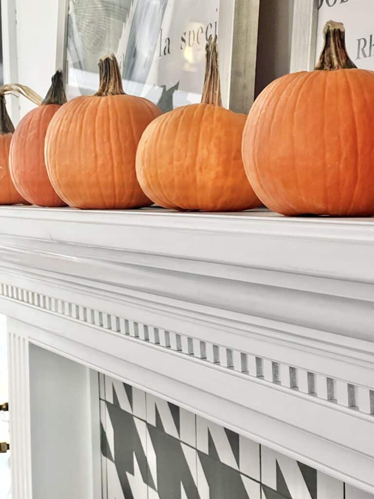 Sugar pumpkins sitting on top of a newly painted fireplace mantel that has been given a makeover.