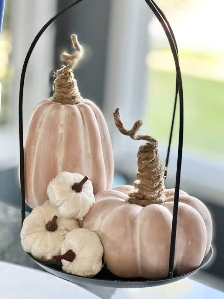 kitchen fall decor ideas: terra cotta pumpkins with twine stems sitting in a metaal weighing scale.